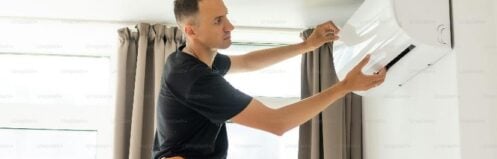 HVAC technician inspecting an indoor residential air conditioning unit before summer.