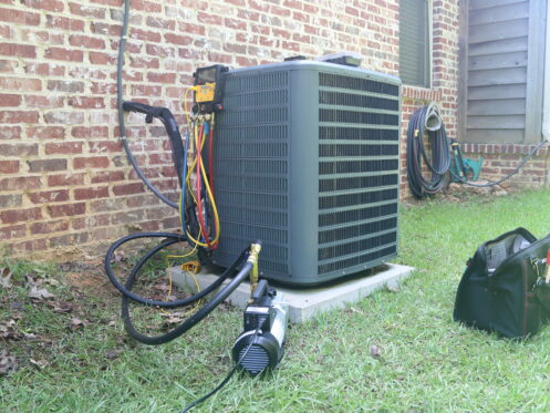 HVAC technician performing air conditioning maintenance during seasonal tune up.