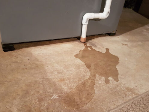 Water leak under furnace showing common HVAC condensation drain issue.